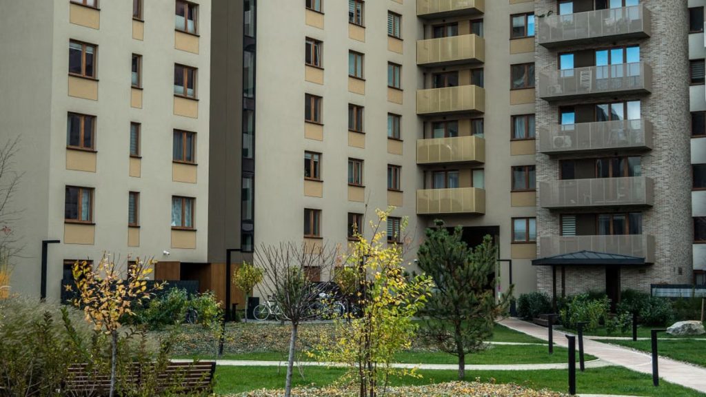 Contemporary high-rise apartment buildings with lush greenery and pathways in the courtyard.