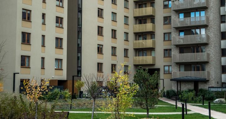 Contemporary high-rise apartment buildings with lush greenery and pathways in the courtyard.